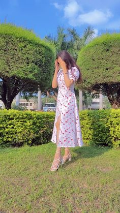 a woman standing in the grass with her hand on her face