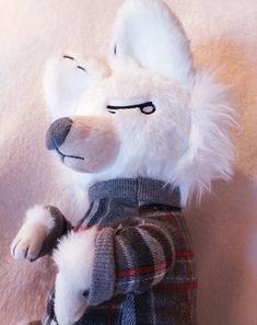 a white stuffed animal wearing a sweater and plaid pants