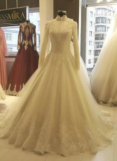 wedding gowns on display in a store window with mannequins behind them