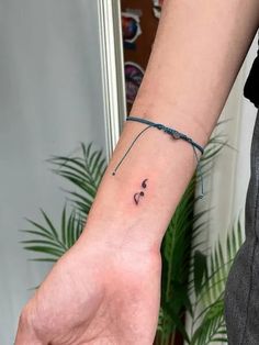 a woman's wrist with a small tattoo on the left side of her arm