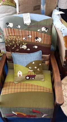 a chair with many pillows on it and some sheep in the pillow case behind it