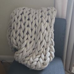 a white blanket sitting on top of a blue chair