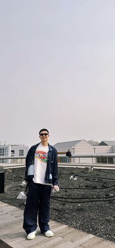 a man standing on top of a wooden dock next to a building and flying a kite