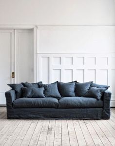 a blue couch sitting on top of a hard wood floor next to a white wall