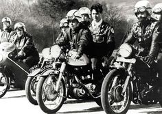 black and white photograph of men on motorcycles with helmeted riders in the foreground