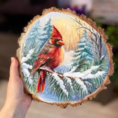 a hand holding up a painted christmas ornament with a red cardinal on it