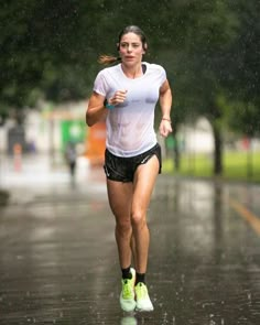 a woman running in the rain with an umbrella