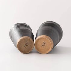 two wine corks sitting side by side on a white surface with chinese characters painted on them