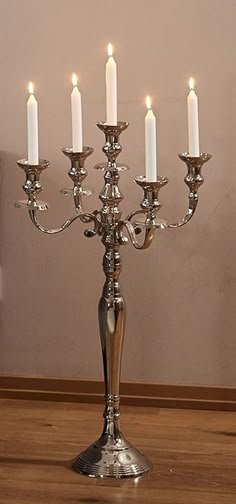 a silver candelabra with five lit candles in it on a wooden table