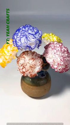 four colorful flowers are in a vase on a white surface with the words new crafts above them