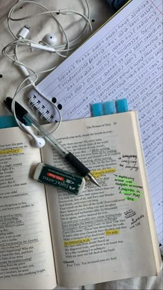 an open book with earbuds and headphones on it next to some books