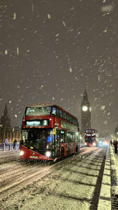 two double decker buses driving down a snowy street