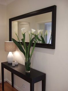 a vase filled with white flowers sitting on top of a table next to a mirror