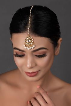 a woman wearing a gold head piece with pearls on it's forehead and eyes