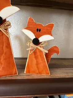 two wooden fox figurines sitting on top of a shelf