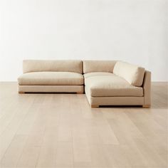 a beige couch sitting on top of a hard wood floor next to a white wall