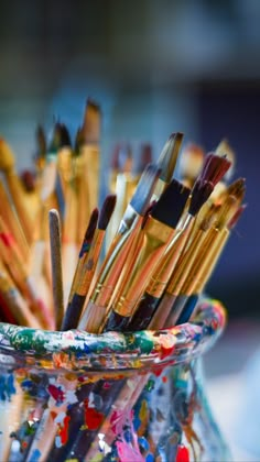 a glass vase filled with lots of paint brushes