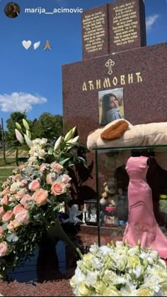 there is a memorial with flowers in front of it and a teddy bear on the ground