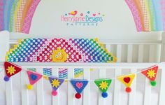 there is a crib with some decorations hanging from it's sides and a rainbow sign above the crib that says happy home designs patterns