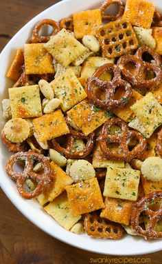 a bowl filled with cheesy crackers and pretzels on top of a wooden table