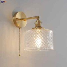 a wall light with a glass shade hanging from it's side on the wall