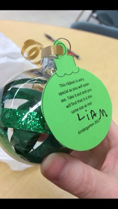 a hand holding a green ornament with a poem on it