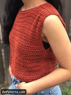 a close up of a woman wearing an orange top with crochet on it