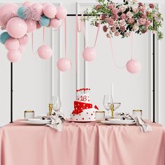 a table topped with a cake and lots of pink balloons hanging from it's ceiling