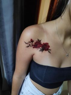 a woman's chest with red roses on her left shoulder and the top half of her body visible