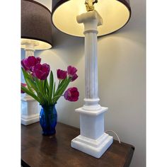 a vase with tulips sits on a table next to a lamp