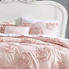 a bed with pink comforters and pillows on it