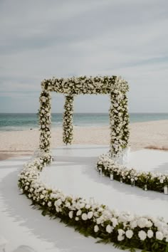 an outdoor ceremony setup with white flowers and greenery in the shape of a heart