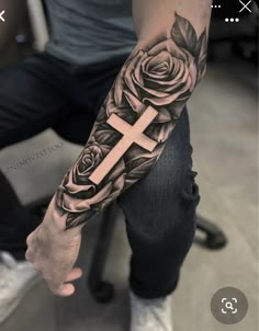 a man with a cross and roses tattoo on his arm