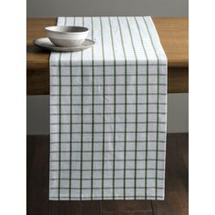 a white and green plaid table runner with a bowl on the edge next to it