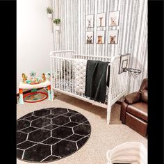 a baby's room with a white crib, black rug and pictures on the wall