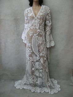 a mannequin is dressed in white lacy crochet and stands against a wall