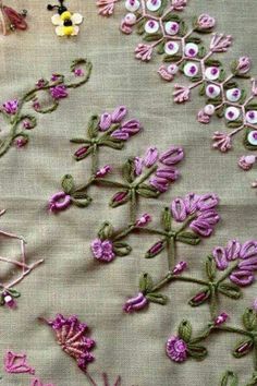 some pink flowers are on a table with white and purple beads in the middle of it