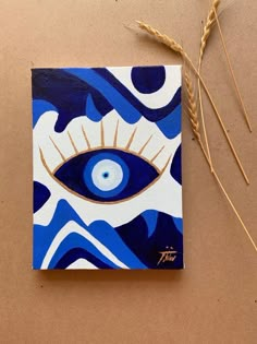 an eye painted on a piece of paper next to some wheat stalks and two straws