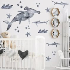 a baby's room decorated in blue and white with shark decals on the wall