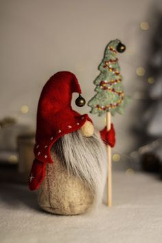 a gnome with a christmas tree on top of it and a wooden stick in the foreground