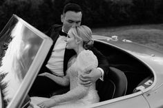 a man and woman are sitting in the back of a convertible car with their arms around each other