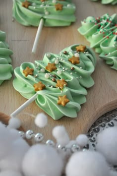 some green and white decorated cookies on a wooden board with candy sticks in the shape of christmas trees