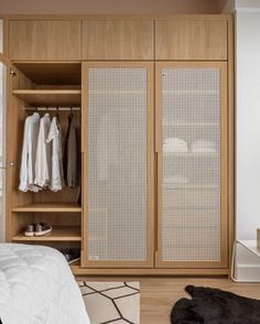 an open closet with clothes on hangers and shoes hanging from the door, next to a bed