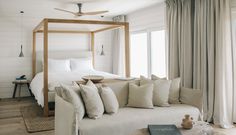 a white couch sitting in front of a bed next to a wooden table with a book on it