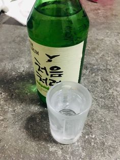 a bottle of alcohol sitting on top of a table next to a glass filled with water