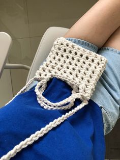 a person sitting on a chair with a crocheted bag in their lap and legs