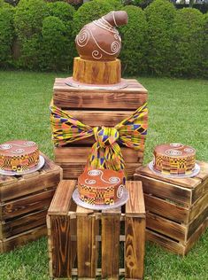 some wooden crates with cakes on them and a bow tie around the top, sitting in the grass