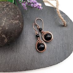 Black Onyx Earrings. Black Onyx Jewelry, Copper Earrings. Black Crystal Earrings, Boho Jewelry DESCRIPTION Handcrafted copper earring featuring a herringbone weave and Black Onyx gemstones.  Black Onyx is a stone of protection, emotional & physical strength.  METAL INFO 🏷️ These earrings were handmade using solid copper wire and antiqued to give them more definition.  🏷️ Please note that unlike some of my other jewellery pieces, these earrings are NOT clear coated. Bare copper naturally darkens through oxidation, but you can easily bring back the shine using a jewellery polishing cloth (included). Your jewellery will be polished before posting. FEATURES Natural gemstone: Onyx Bead size: 1 cm Dimensions: these earring hang about 3.5 cm from the piercing and are 1.5 cm wide WHAT'S INCLUDED Black Teardrop Earrings With Black Beads, Handmade Black Dangle Earrings, Black Beaded Round Earrings, Black Metal Dangle Earrings, Black Teardrop Metal Earrings, Black Metal Teardrop Earrings, Black Teardrop Jewelry Making Supplies, Gift Metal Earrings With Black Beads, Black Dangle Earrings With Ear Wire