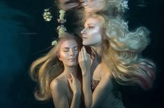 two women are underwater with their hair blowing in the wind