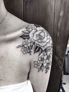 a black and white photo of a woman's shoulder with flowers on the side